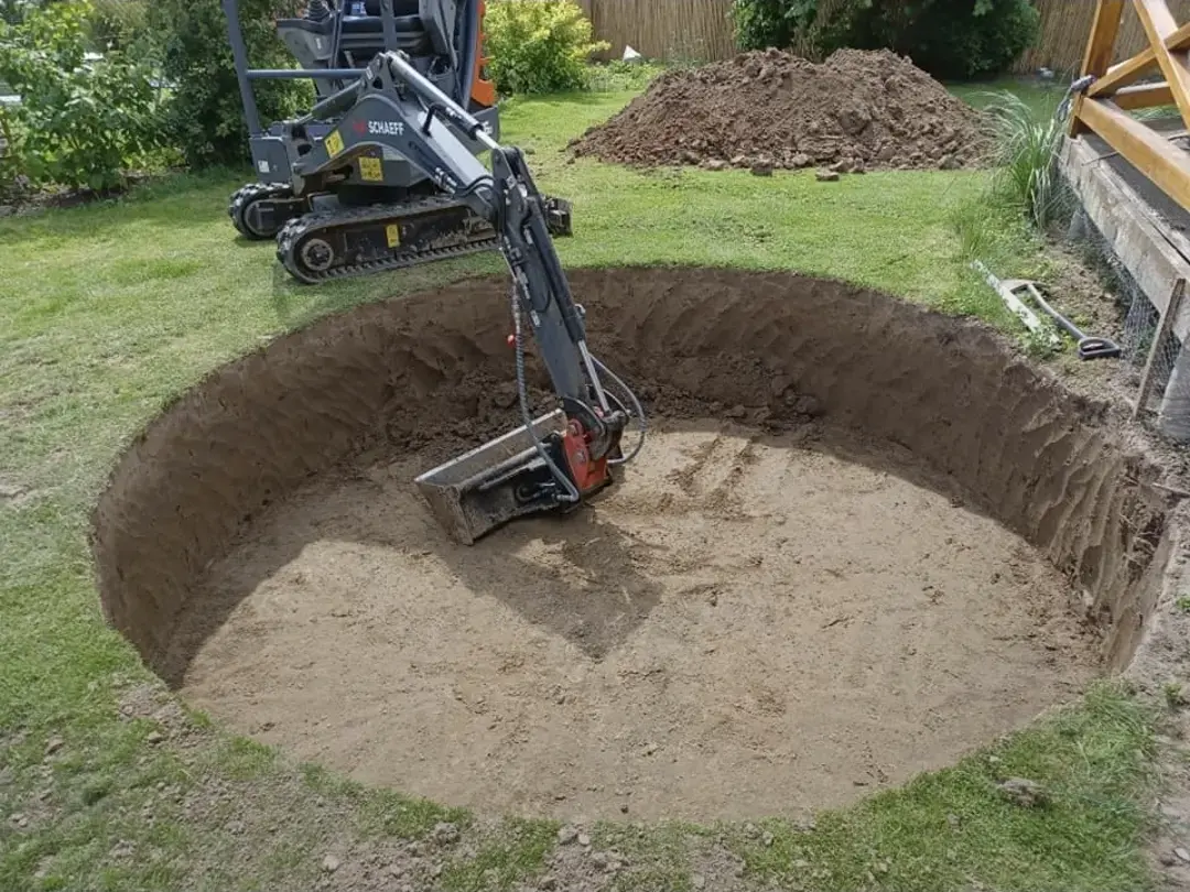 Minibagger bei Erdarbeiten für einen Gartenteich