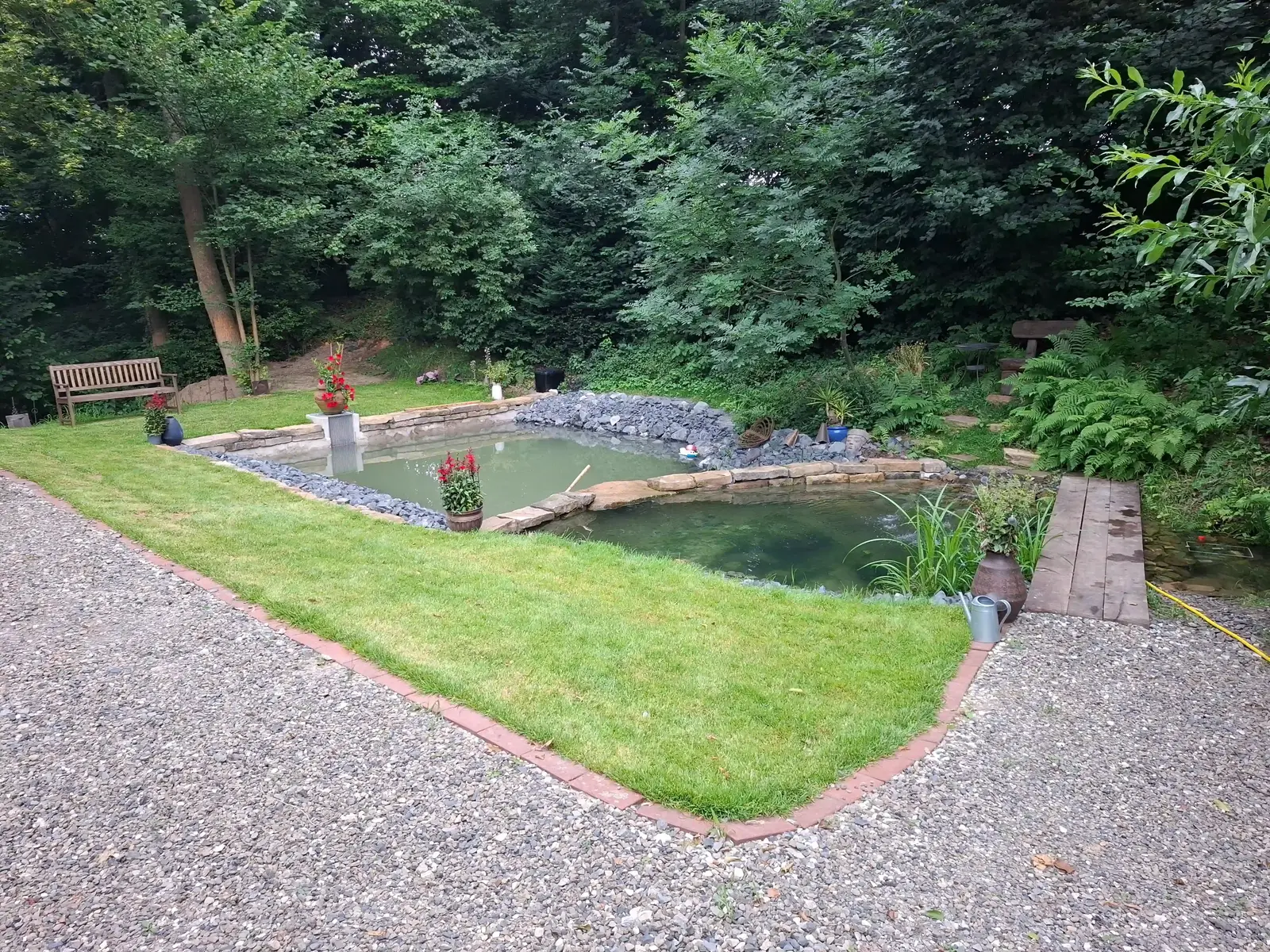 Fertig gestalteter Gartenteich mit Rasen und Natursteinen